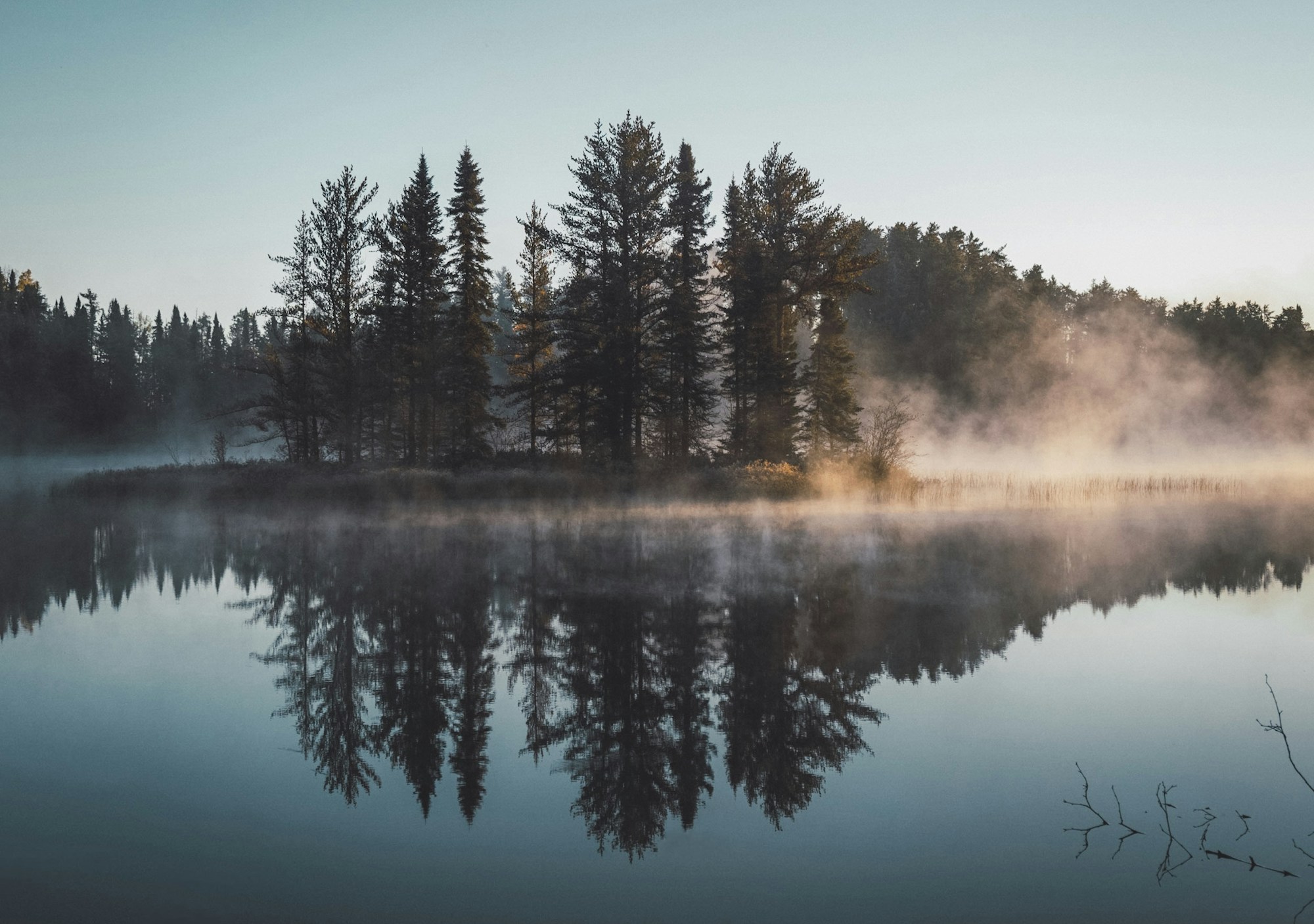 Hommikune udu ja päikesevalgus metsase järve kohal